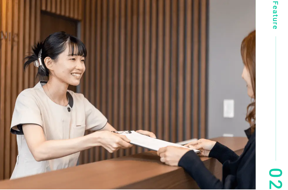 歯医者の受付スタッフが問診票を渡している